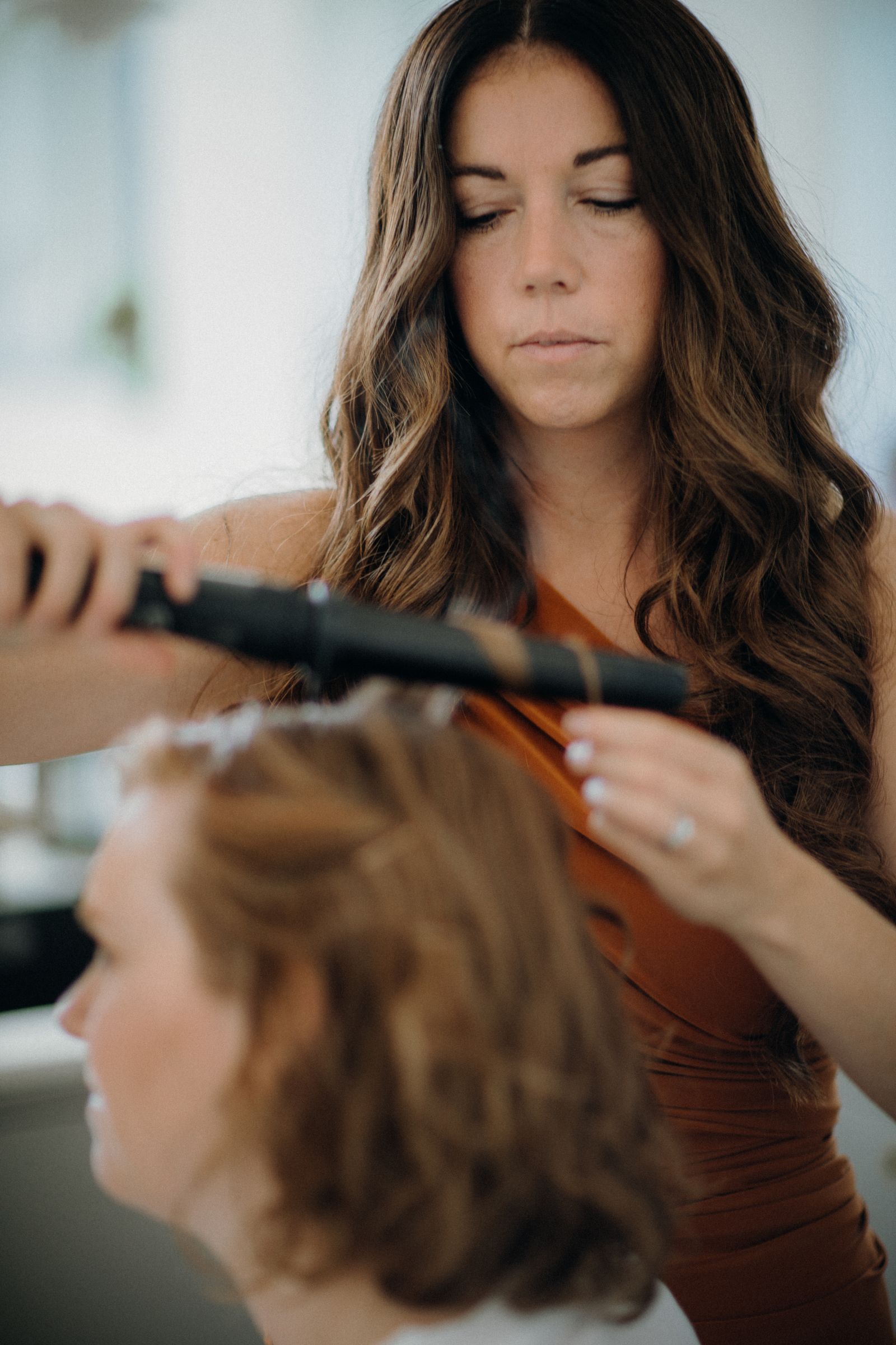 A stylist curling a client's hair with a wand