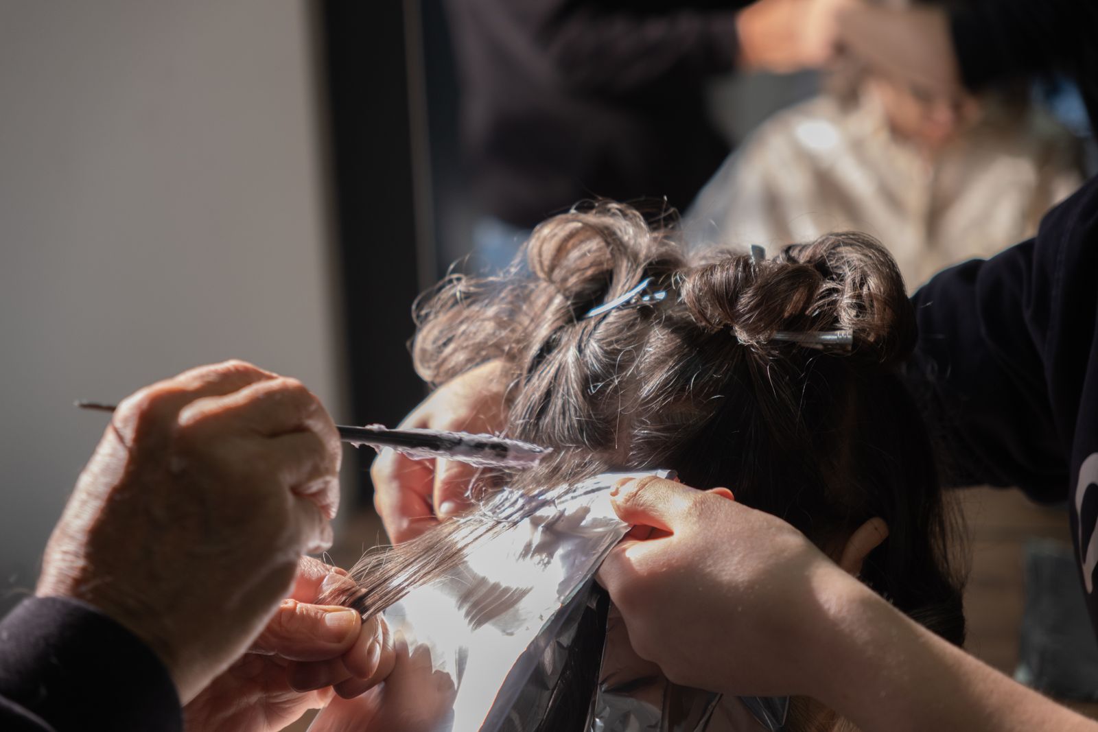 A colorist folding foil highlights through a client's hair