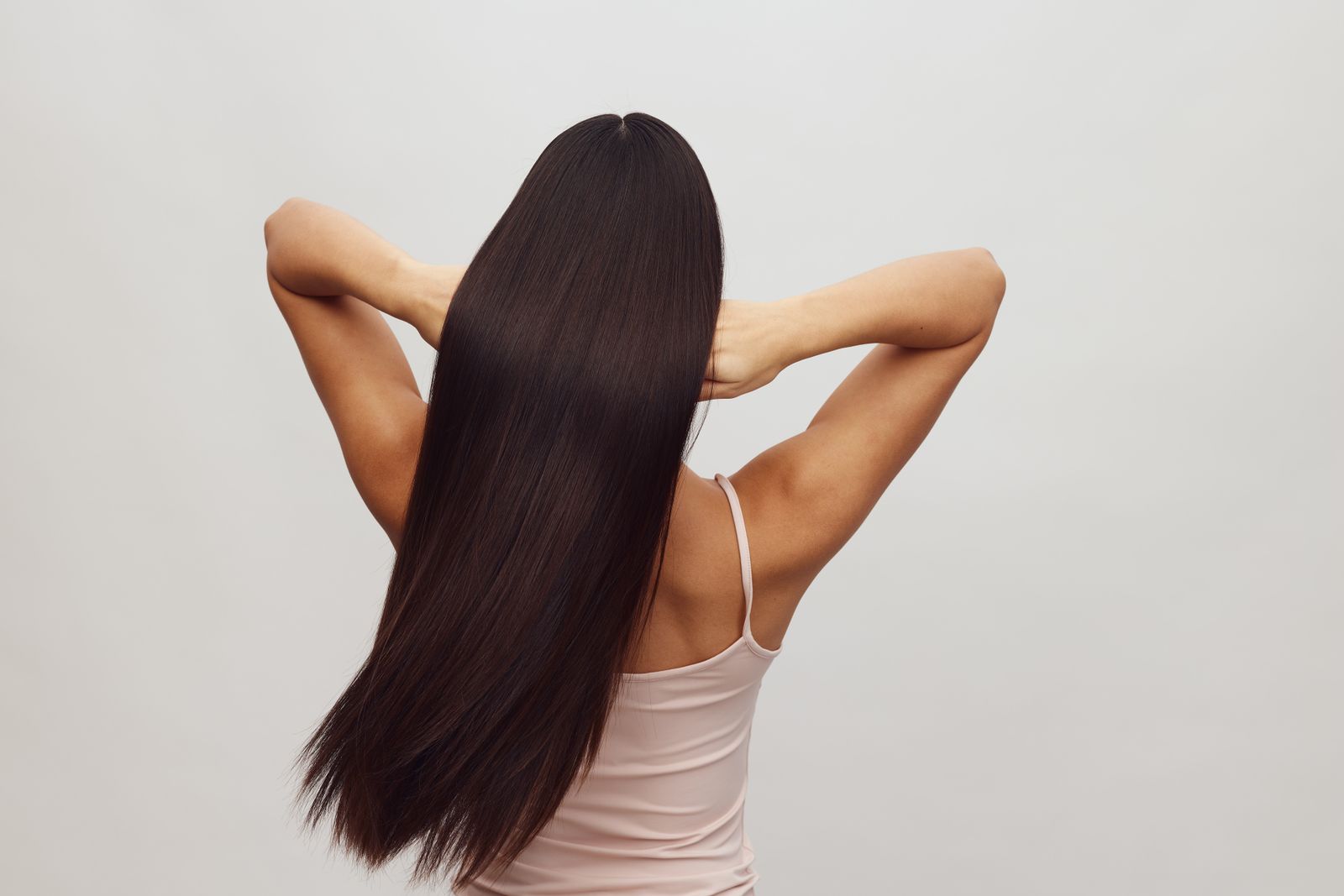 A woman with long, straight, glossy dark hair seen from behind