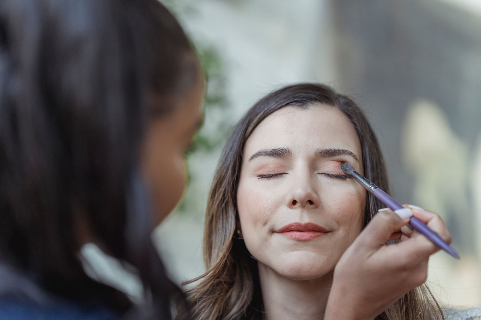 A makeup artist applying eyeshadow to a client