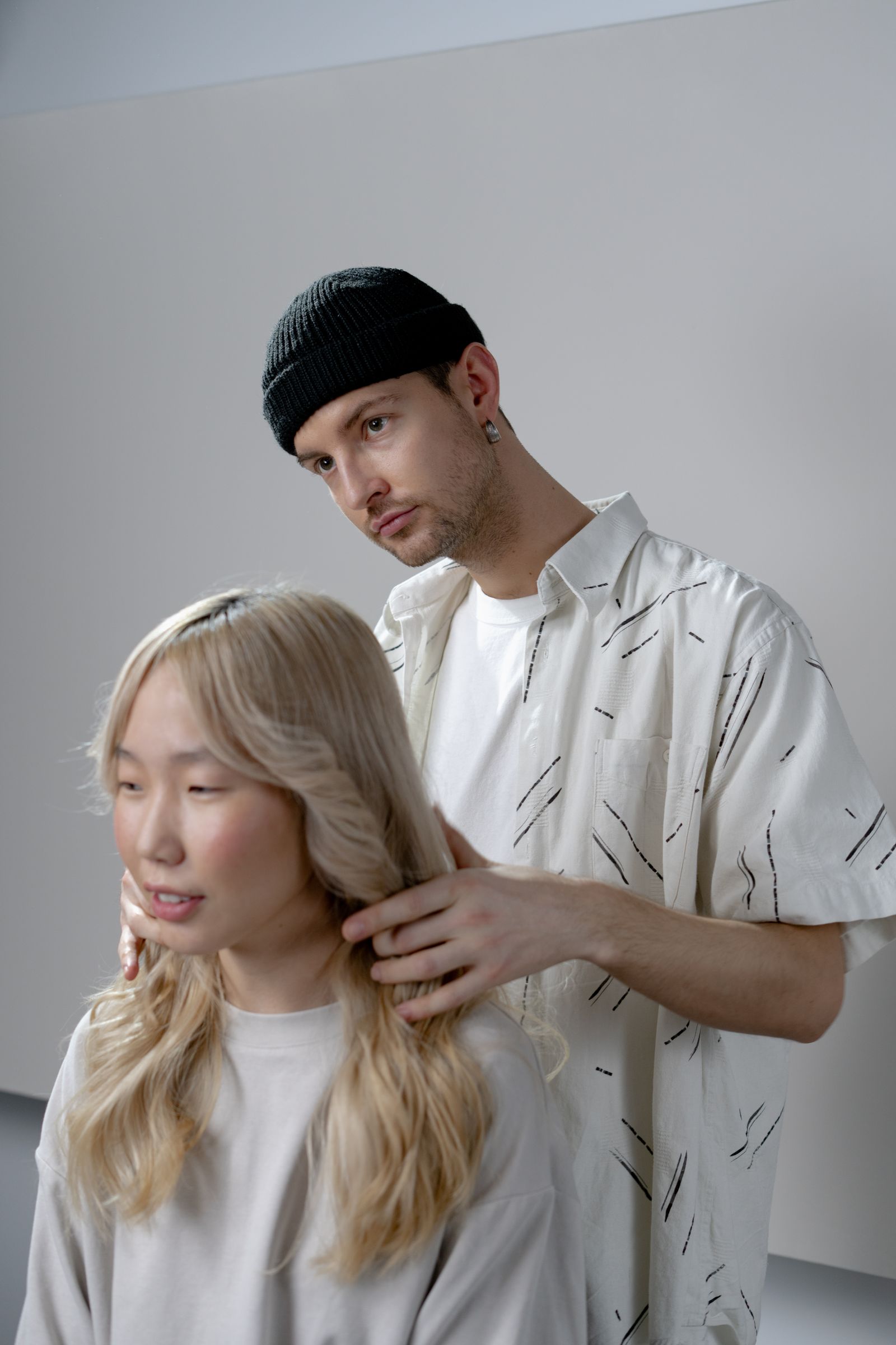 A hairstylist carefully styles a woman's hair in a modern salon setting.